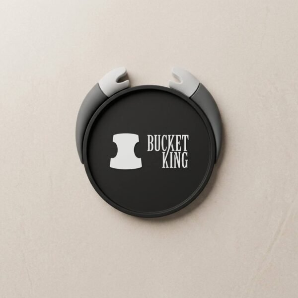 Custom 3D soft PVC coaster with a black round body and gray dimensional handles, featuring white "BUCKET KING" lettering and icon on the front, on a light beige solid-color background