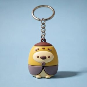 Custom 3D PVC Keychains Adorable Cartoon Animal Charms A yellow cartoon animal 3D PVC rubber keychain featuring a chubby body, brown ruffled skirt, and a matching top accent. The surface is glossy and smooth, attached to a sturdy metal chain.
