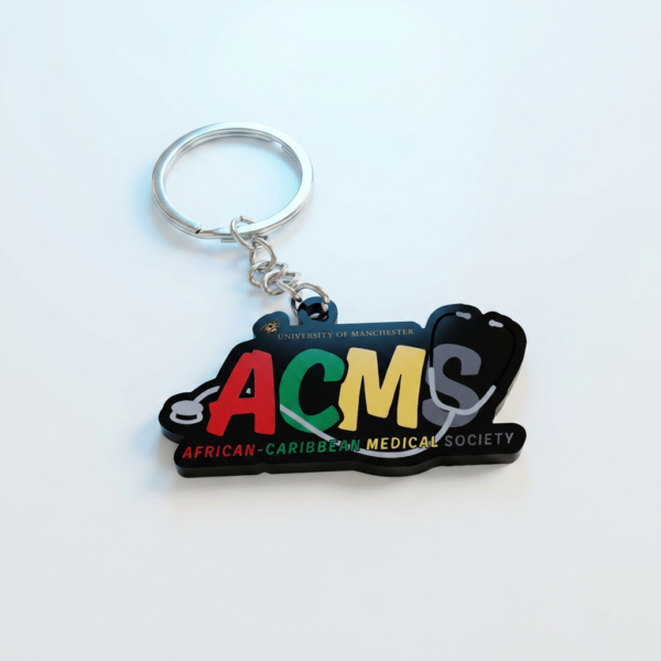 Custom Acrylic Keychains University Society & Medical Association Logo Charms A modern custom acrylic keychain featuring a black rectangular base. It displays the large, colorful "ACMS" acronym (Red, Green, Yellow, Gray) representing the African-Caribbean Medical Society. Gold text reads "UNIVERSITY OF MANCHERSTER" with a mini crest, while white and red text below spells out the full society name. A subtle white stethoscope graphic is visible behind the letters. Attached via a short metal chain to a silver split ring.