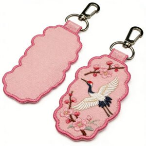 Custom Embroidered Keychain Chinese Style Crane & Cherry Blossom Auspicious Cloud Charm Pink auspicious cloud-shaped embroidered keychain featuring an embroidered red-crowned crane in flight with blooming pink cherry blossom branches on the front, in fresh, understated colors, with a metal lobster clasp, displayed front and back on a pure white background