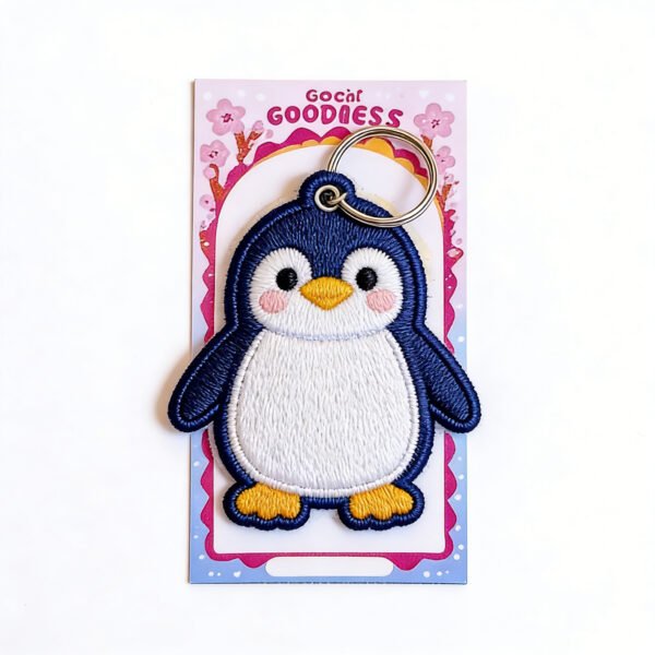 Custom embroidered penguin keychain with blushing cheeks on a pink & blue card, perfect for gifts & party favors
