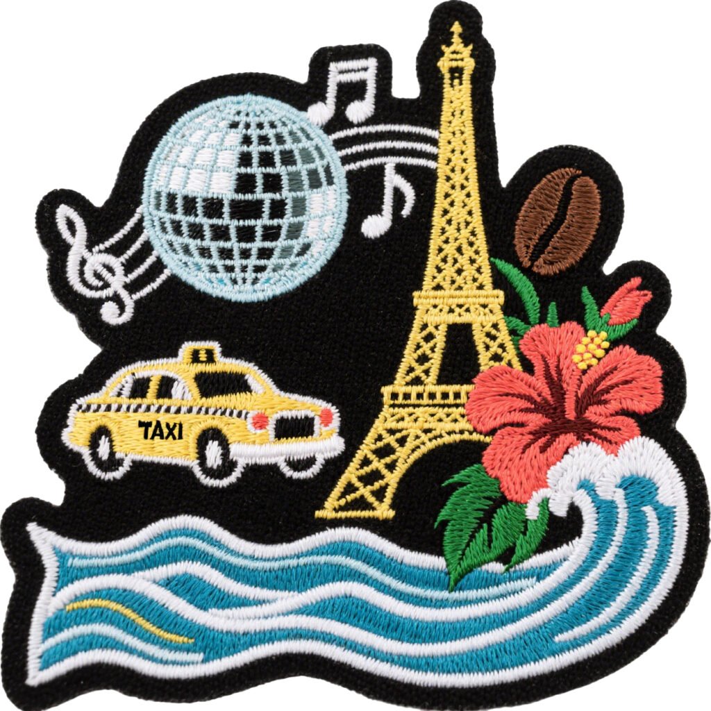 Colorful embroidered patch on a black base featuring a yellow Eiffel Tower, pink flower, ocean waves, yellow taxi, and disco ball, displayed on a pure white background