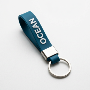 Custom Silicone Keychain Minimalist Letter Webbing Charm Navy blue (or lake blue) silicone rubber keychain featuring raised white "OCEAN" lettering. Fitted with a silver-plated metal clasp and standard key ring, displayed against a white background.