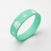 Mint green silicone wristband featuring cute cartoon dinosaur, dinosaur footprint, and bird-shaped white debossed prints on the surface, displayed on a pure white background