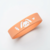 Bright orange food-grade silicone wristband featuring adorable white cartoon bunny, carrot, and heart prints, soft and lightweight design for kids' daily wear and outdoor mosquito protection, displayed on plain white background.