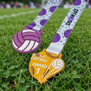 Custom Soft PVC Medal Two vividly colored soft PVC medals — one in a purple volleyball design and the other in a yellow shield design printed with "DL Kids FOOTBALL AWARD 1" lettering and a volleyball motif — both paired with white polyester ribbons printed with purple volleyballs and brand logos