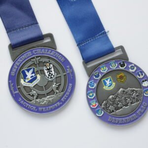 Custom Zinc Alloy Metal Medal Military Tactical Defender Challenge Event Commemorative Medal Two zinc alloy metal medals with a purple-and-silver dual-tone electroplating finish. The left medal features "DEFENDER CHALLENGE" lettering, a tactical figure running with a rifle, and an "AF SECURITY FORCES CENTER" badge on the front; the right medal features "DEFENDER FLAG" lettering, a snow mountain march embossed scene, and multiple commemorative badges, both paired with blue polyester ribbons, displayed on a pure white background