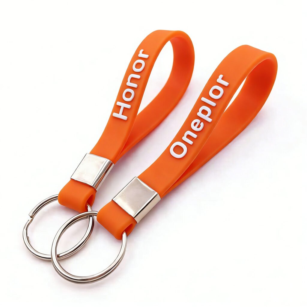 A pair of vibrant orange custom silicone wristband keychains. The flexible loops feature bold white 3D raised text reading "Honor" and "Oneplor." Each is fitted with a rectangular silver metal buckle and a double metal ring connector, combining a minimalist look with high-visibility safety and anti-loss functionality.
