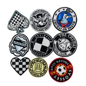 A collection of nine custom flat embroidery patches. Designs include an Ace of Spades playing card, a vintage eagle crest, "THE CHUHAI OFFICIAL CLUB" text logo, "L.I. SOCCER CLUB" badge, "GOSFORTH OWEMIANS" racing flag emblem, a flask and racket academic society logo, a light blue helmet with crossed bones, a red and black checkered heart, and a cartoon hamburger. All patches feature tightly stitched merrowed edges.