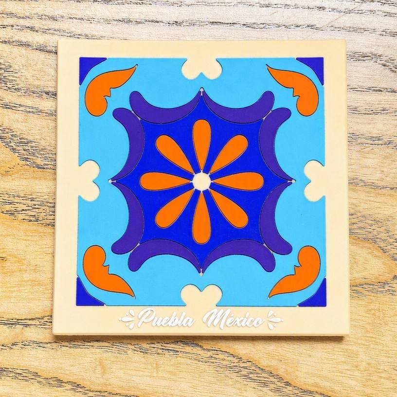 Square custom PVC coasters featuring a blue and orange Talavera geometric star-flower pattern on a cream base; text reads "Puebla México"; inspired by traditional Mexican pottery.