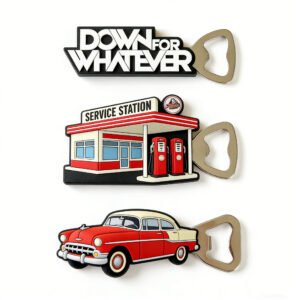 Custom PVC soft rubber magnetic bottle opener featuring vintage Americana theme with "DOWN FOR WHATEVER" slogan, gas station scene, and classic car graphics; equipped with strong back magnet for adherence to refrigerators or metal surfaces, combining utility with decor.