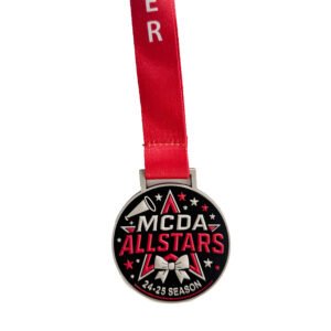 Custom PVC soft rubber medal with black base and red-white-blue contrast screen printing; features embossed "MGDA ALLSTARS" text, silver bow, referee whistle and five-pointed star; topped with red athletic ribbon, designed for sports competitions and fun events.