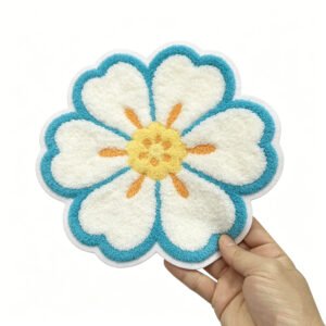 3D eight-petal flower towel embroidery patch featuring pure white petals with a bright sky-blue wavy edge and a warm yellow-orange stamen center; crafted with plush chenille texture and white merrowed edging, ideal for decorative accents on kidswear, sweaters, canvas bags or hats.