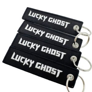 Set of 4 identical black rectangular embroidered keychains featuring bold white Old English font "LUCKY GHOST" text with fine merrowed edges; finished with a silver metal split ring, embodying dark streetwear and punk aesthetics for everyday carry decor.