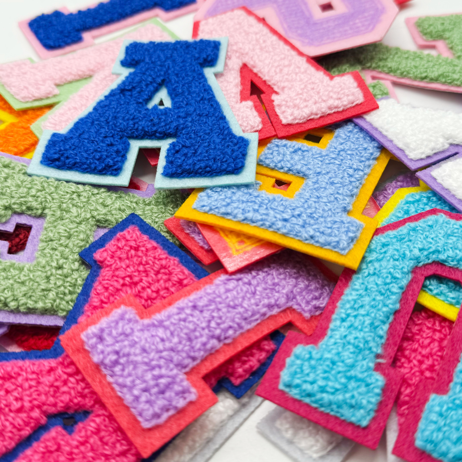 Colorful chenille letter patches with raised yarn texture and contrasting felt borders