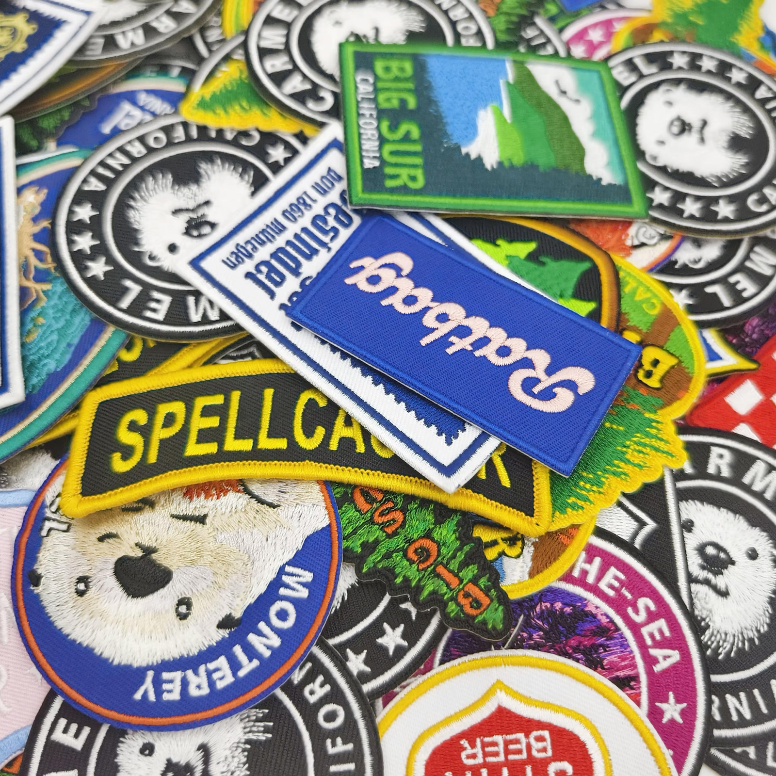 Assorted custom embroidered patches with colorful logos, lettering and stitched borders