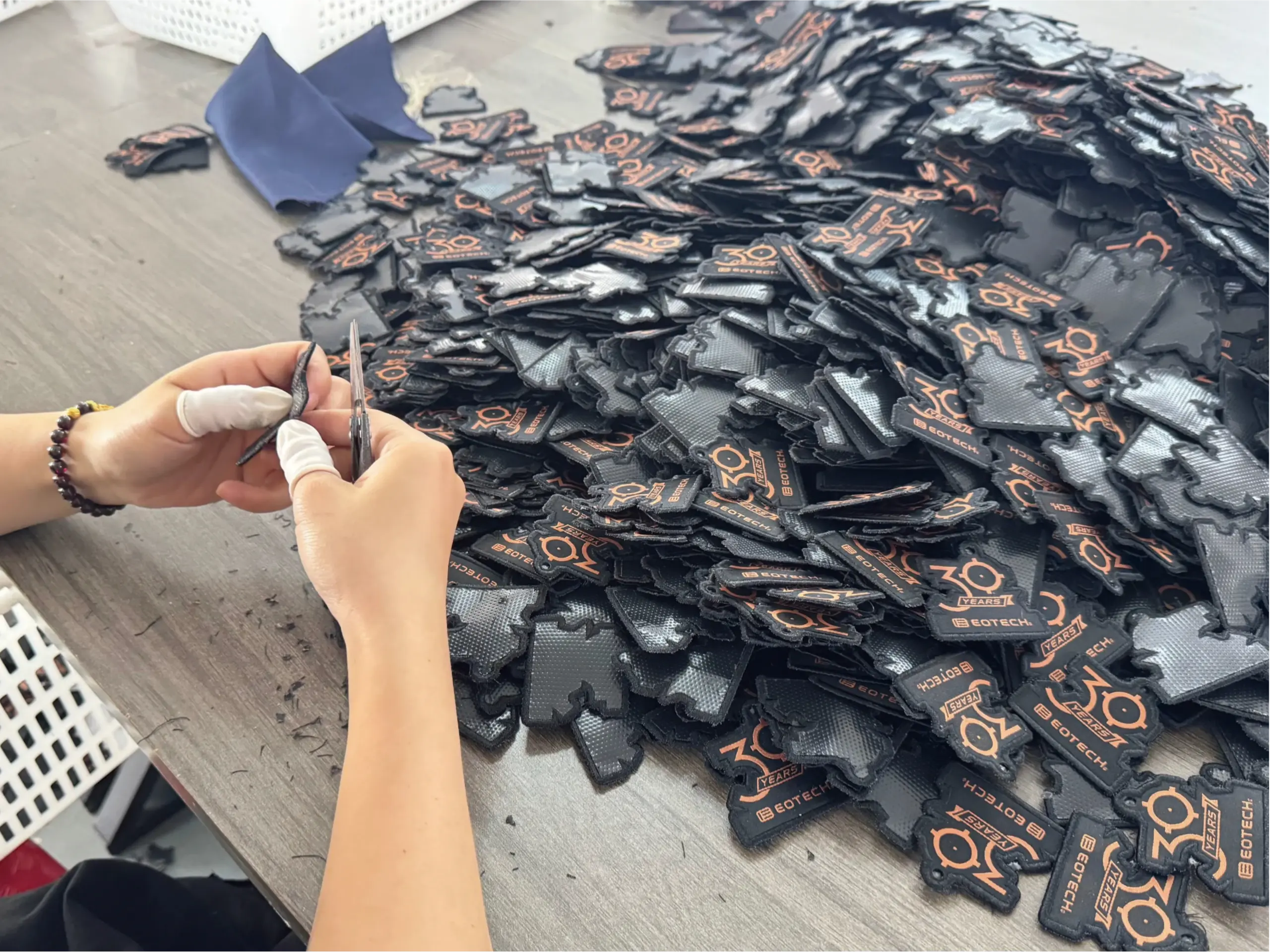 Worker trimming custom promotional product components during quality review